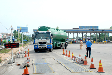 Cảnh sát giao thông và Thanh tra Sở GTVT hướng dẫn phương tiện vào trạm cân tải trọng xe trên quốc lộ 1A.  
